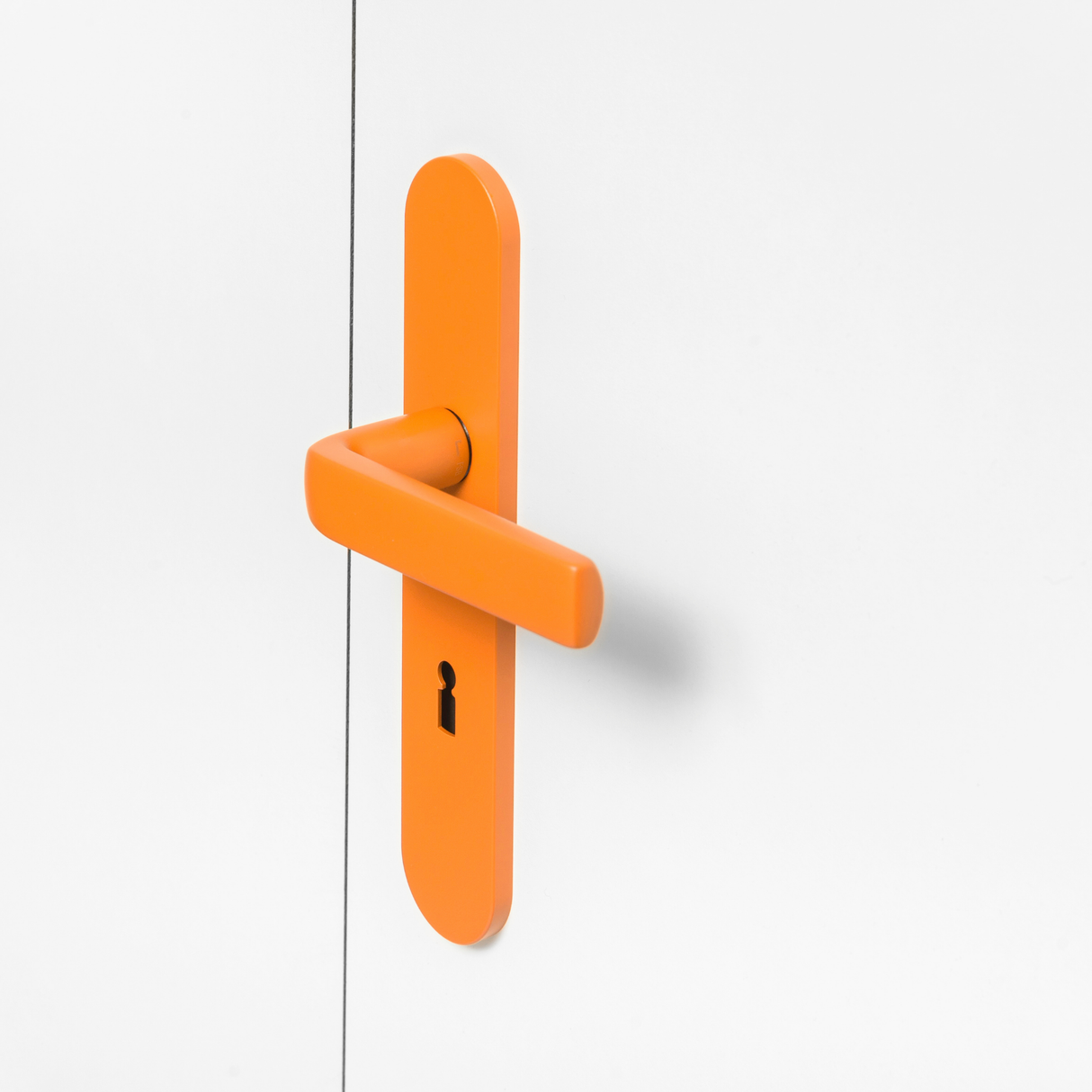 FSB 1267 Türdrücker mit Langschild in Les Couleurs® Le Corbusier® Orange auf weißer Tür, Seitenansicht.