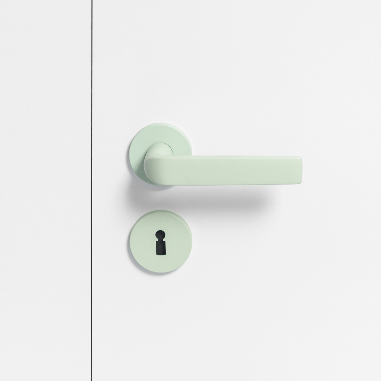 FSB 1267 Türdrücker mit Rundrosetten in Les Couleurs® Le Corbusier® Vert Anglais Pâle auf weißer Tür, Frontansicht.