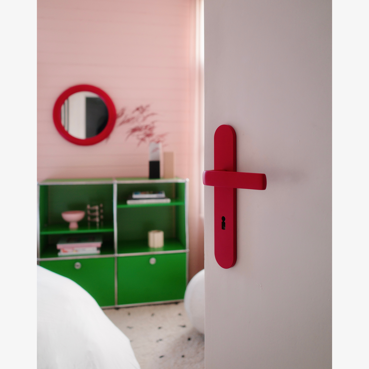 Rote FSB 1267 Langschildgarnitur in Les Couleurs Le Corbusier rouge vermillon an heller Tür im Wohninterieur.