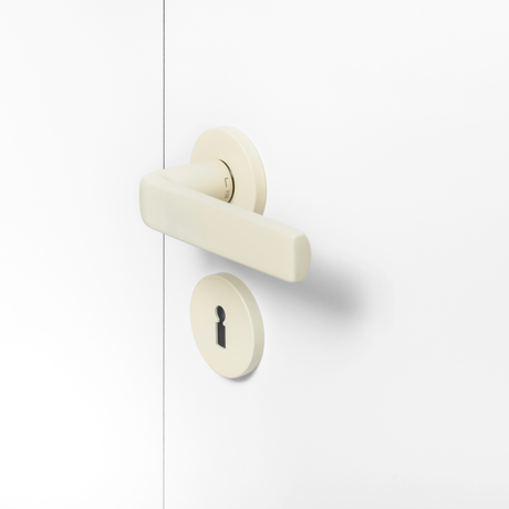 FSB 1267 Türdrücker mit Rundrosetten in Les Couleurs® Le Corbusier® Blanc auf weißer Tür, Seitenansicht.