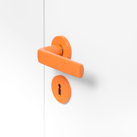 FSB 1267 Türdrücker mit Rundrosetten in Les Couleurs® Le Corbusier® Orange auf weißer Tür, Seitenansicht.